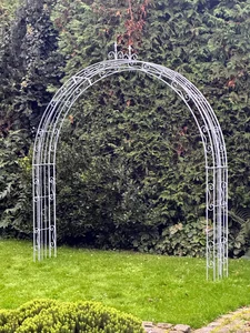 Blick durch einen schmiedeeisernen Rosenbogen im Garten